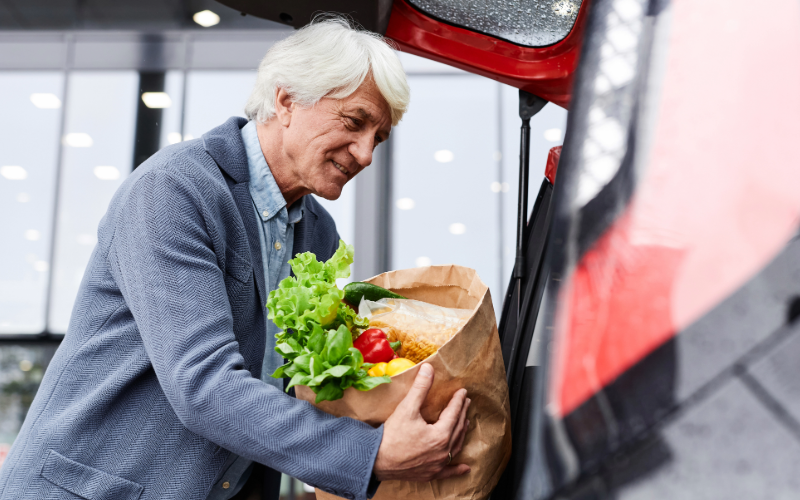 A wearable monitoring device tracks this man's vital signs as he loads groceries into the back of his car.