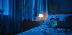 Alarm clock on nightstand in dim bedroom, representing sleep data monitoring in skilled nursing facilities