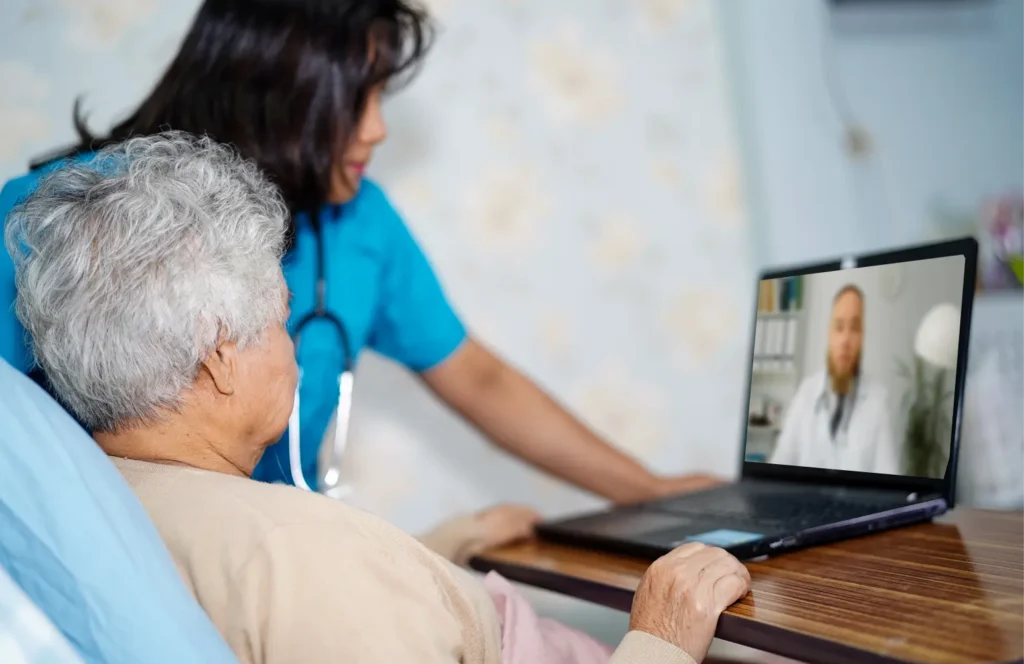 A nurse assists a female SNF resident with her telehealth call with her doctor.