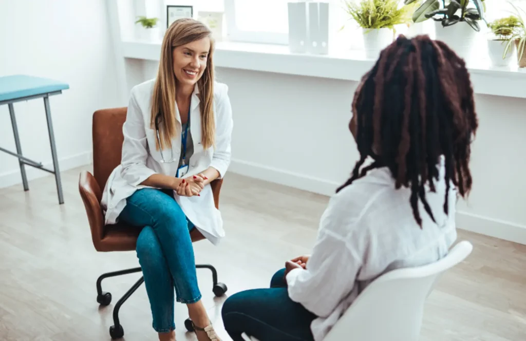 Counselor in a behavioral health unit sits in an office chair across from a young patient.