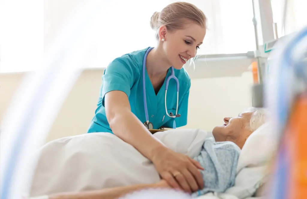 Nurse checks on an elderly female patient in the medical-surgical unit.