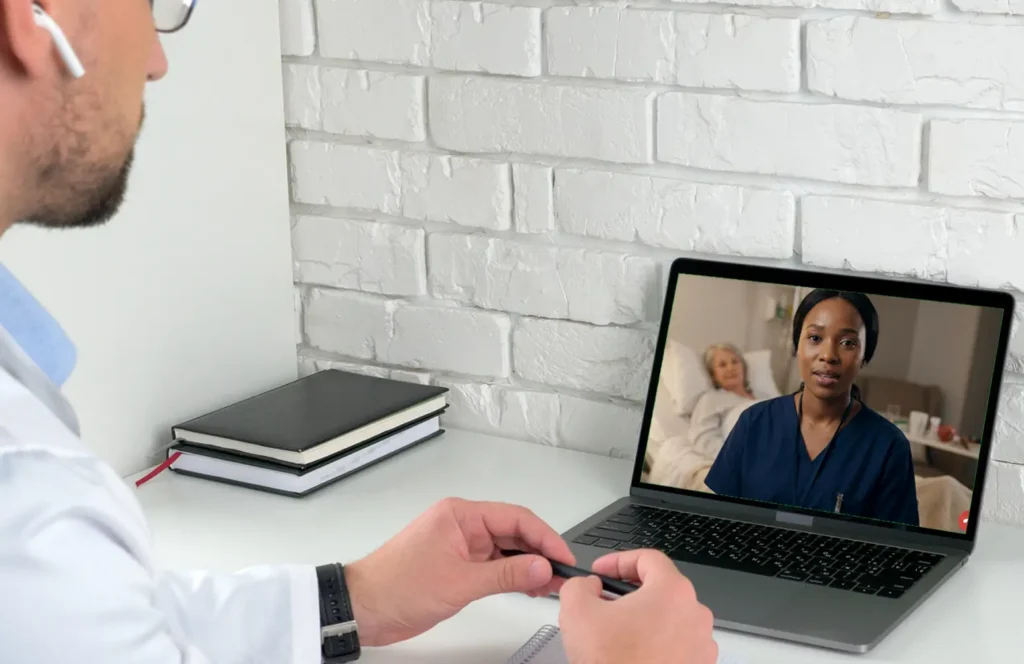 Nurse in a skilled nursing facility consults from the resident's bedside with a physician via video call.